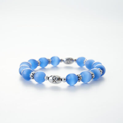 A periwinkle beaded bracelet with metal beads in between, a cancer ribbon carved in the center