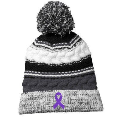 back and white wool winter hat with black and white pom pom on top, with purple cancer ribbon on the rim