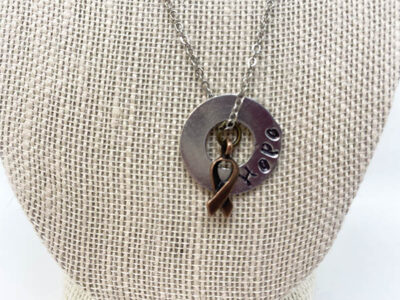 metal doughnut pendant necklace with "hope" engraved on it, a bronze ribbon charm