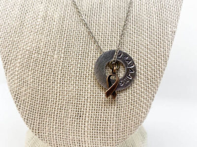 metal doughnut pendant necklace with "survivor" engraved on it, a bronze ribbon charm