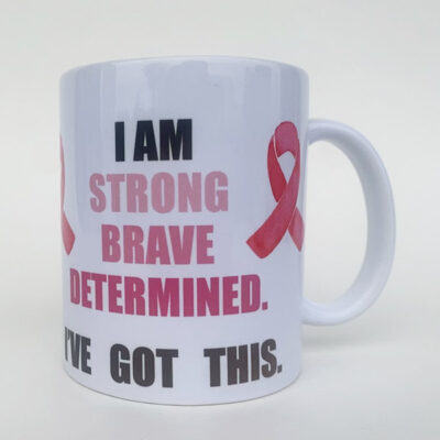 white coffee, bold text reading I am "Strong Brave Determined" (All in pink) I've got this, with two pink cancer ribbons on either side of text, the rest of the text is black