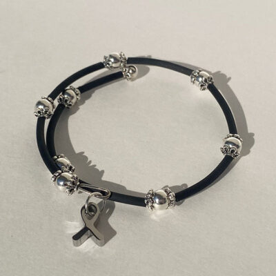 cross wrapped bracelet with metal beads and a metal cancer ribbon charm