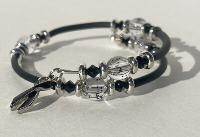 bracelet that crosses itself with big sparkle beads and a black cancer charm on one end