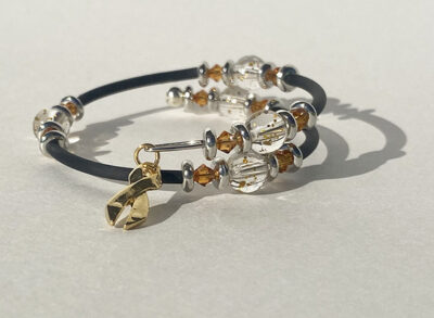 bracelet that crosses itself with big sparkle beads and a peach cancer charm on one end