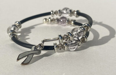 bracelet that crosses itself with big sparkle beads and a gray cancer charm on one end