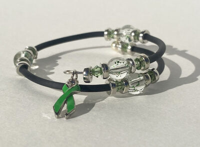 bracelet that crosses itself with big sparkle beads and a emerald green cancer charm on one end