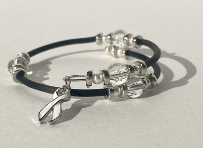 bracelet that crosses itself with big sparkle beads and a white cancer charm on one end