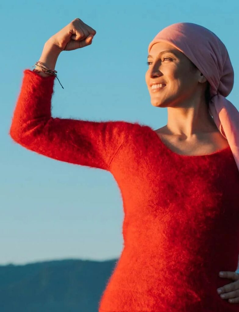 woman flexing her arm with pink head scarf and thread bracelets