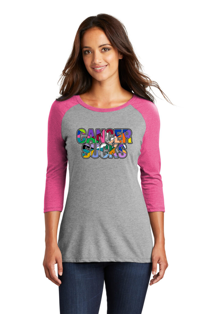 Image showing the Multicolored Cancer Sucks Ladies Raglan that has a heather grey torso, with pink raglan sleeves and the multicolored cancer sucks graphic printed on the front of the shirt