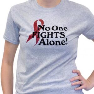 Group image showing our No One Fights Alone® T-shirt that has the wording "No One Fights Alone!" and a cancer awareness ribbon printed on the front of the t-shirt which is a light heather grey color.