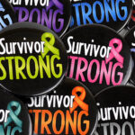 Image showing our cancer survivor buttons that are 2.25 inch diameter and have the words 'Survivor Strong' with a cancer awareness ribbon printed on each button.