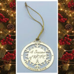 image showing our 'Season of Hope 2025 holiday ornament' one in the gold finish. Each ornament is laser cut with the wording, "A Season of Hope" in the center and a snowflake pattern connecting to an outer circle that has the year, 2025, with the words, "CHOOSE HOPE" at the bottom of the ornament.